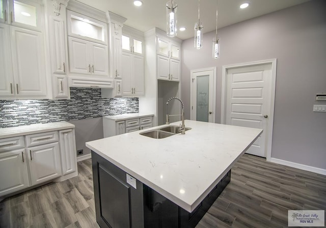 kitchen with decorative backsplash, dark wood-style floors, white cabinetry, pendant lighting, and a sink