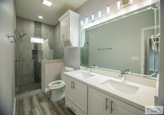 bathroom featuring toilet, a stall shower, a sink, and wood finished floors