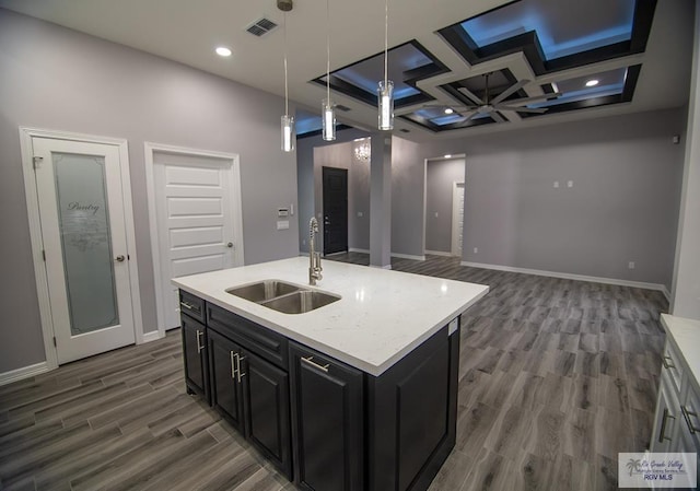 kitchen with dark cabinets, light countertops, a sink, and visible vents