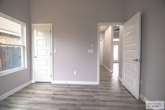 spare room featuring wood finished floors, a wealth of natural light, and baseboards