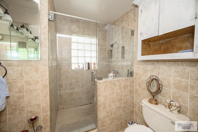 bathroom with toilet, a shower with door, and tile walls