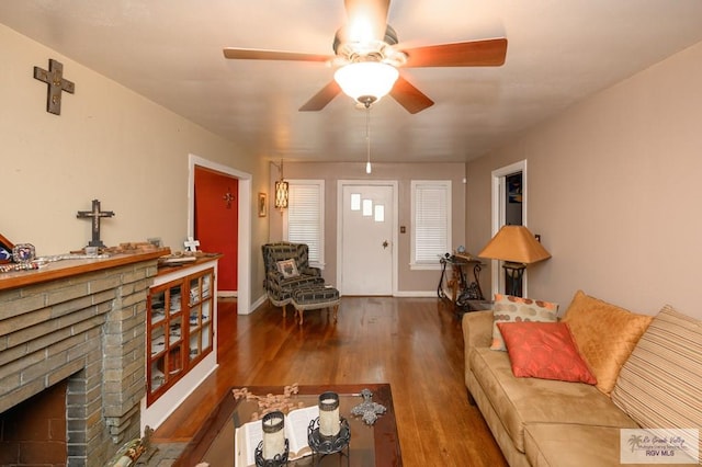 living room featuring dark hardwood / wood-style floors, ceiling fan, and a brick fireplace