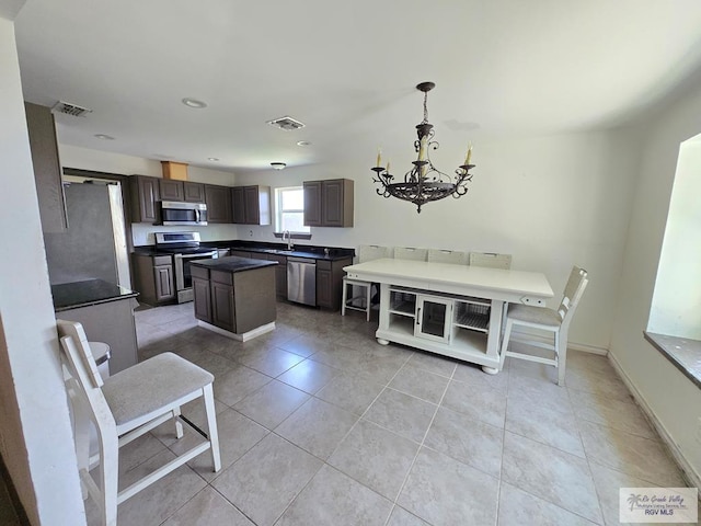 4727 Las Palomas St, Brownsville, TX 78521 - kitchen featuring appliances with stainless steel finishes, a kitchen island, a chandelier, dark countertops, and light tile patterned flooring