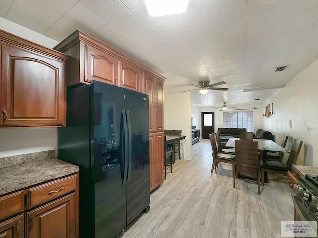 700 N Illinois Ave, Weslaco, TX 78596 - kitchen with black refrigerator with ice dispenser, a ceiling fan, stainless steel gas range, light wood finished floors, and open floor plan