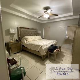 bedroom with light tile patterned floors, a raised ceiling, and ceiling fan