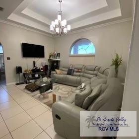 tiled living room featuring a raised ceiling, ornamental molding, and an inviting chandelier