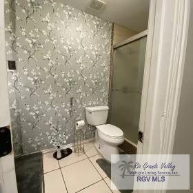 bathroom featuring tile patterned flooring, toilet, and walk in shower