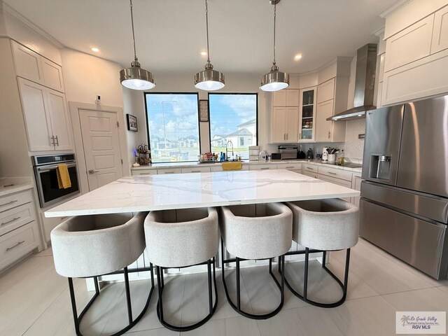 1992 Lulu St, Brownsville, TX 78577 - kitchen featuring stainless steel appliances, wall chimney exhaust hood, a breakfast bar, decorative backsplash, and recessed lighting