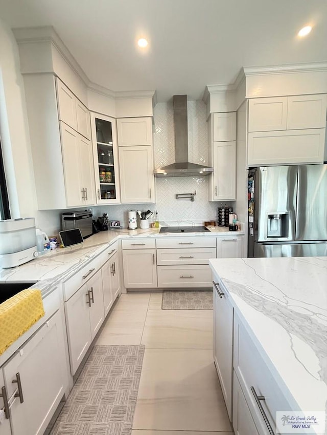 1992 Lulu St, Brownsville, TX 78577 - kitchen with stainless steel fridge with ice dispenser, wall chimney exhaust hood, tasteful backsplash, light stone counters, and black electric cooktop