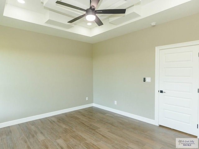 unfurnished room with a raised ceiling, ceiling fan, and light hardwood / wood-style floors