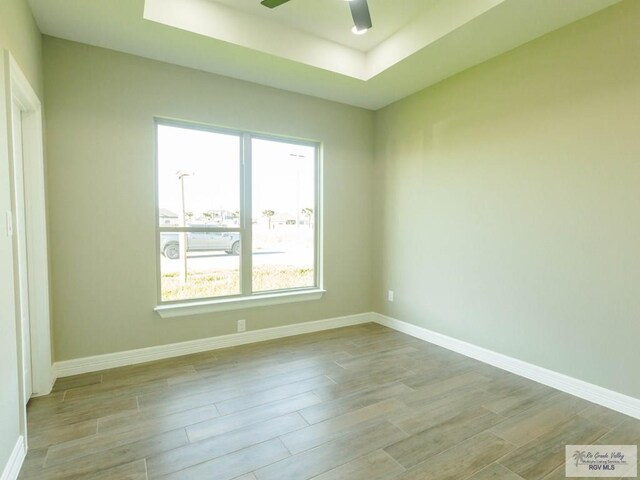 unfurnished room featuring ceiling fan, a raised ceiling, and a wealth of natural light