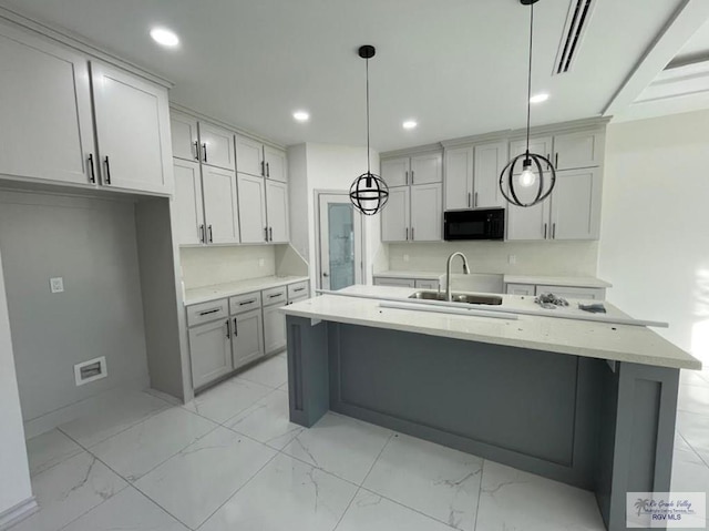 kitchen featuring gray cabinets, sink, an island with sink, and pendant lighting