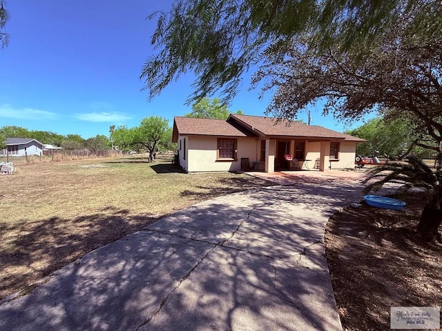 ranch-style home with stucco siding, driveway, a front lawn, and fence