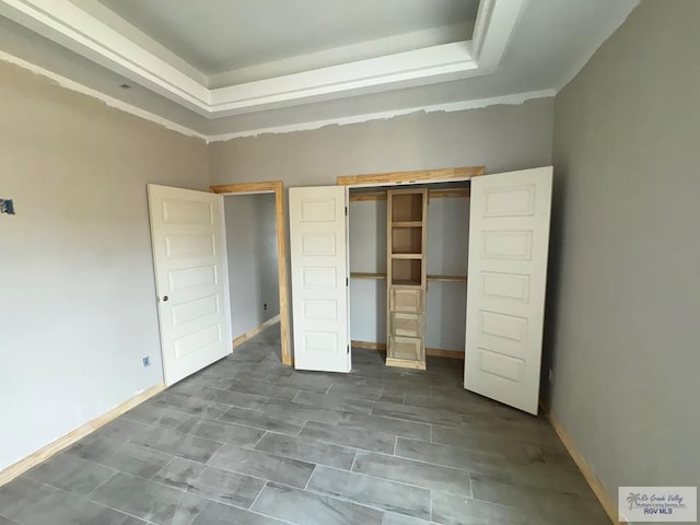 unfurnished bedroom with a raised ceiling and a closet