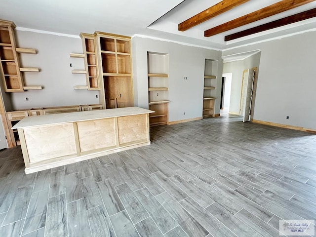 interior space featuring beamed ceiling, built in features, light wood-type flooring, and crown molding