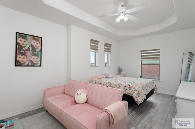 bedroom featuring a raised ceiling, ceiling fan, and hardwood / wood-style floors