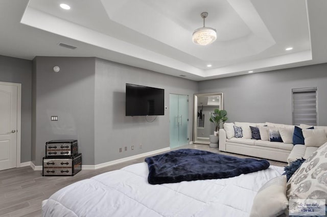 bedroom with hardwood / wood-style floors and a raised ceiling