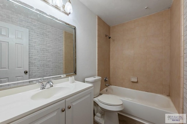 full bathroom with tiled shower / bath, vanity, and toilet