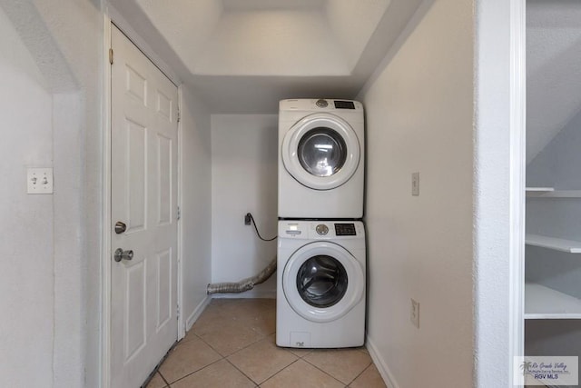 clothes washing area with stacked washer and clothes dryer and light tile patterned flooring