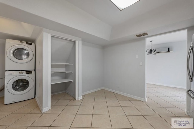 laundry area with stacked washing maching and dryer, built in features, light tile patterned floors, a notable chandelier, and a wall unit AC