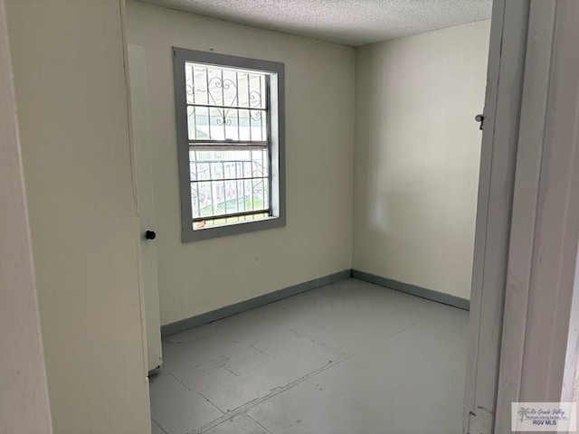 empty room featuring baseboards and a textured ceiling