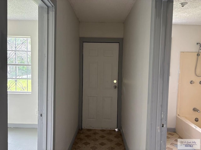 interior space with a textured ceiling, tile patterned floors, and baseboards