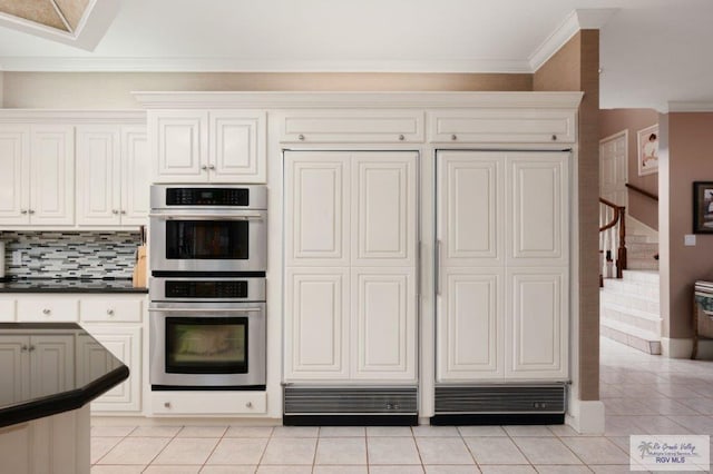 kitchen featuring white cabinetry, light tile patterned floors, ornamental molding, double oven, and backsplash