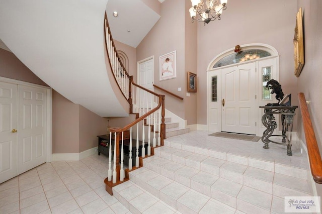 entryway featuring light tile patterned floors, a notable chandelier, and high vaulted ceiling