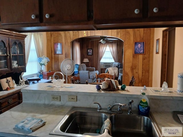 kitchen with ceiling fan, wooden walls, and sink