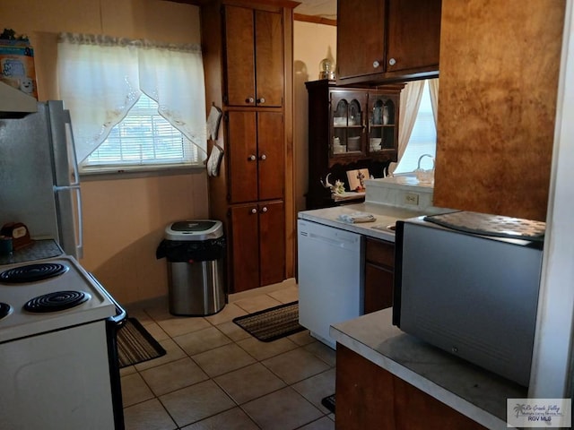 kitchen featuring light tile patterned floors, fridge, range with electric cooktop, and dishwasher