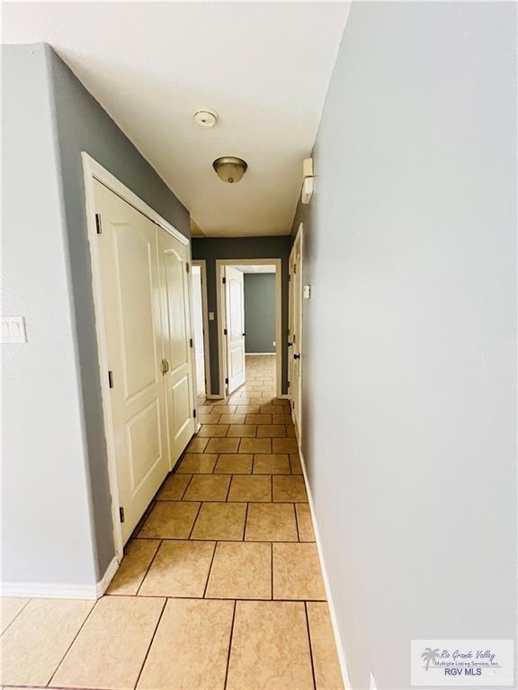 corridor featuring baseboards and light tile patterned flooring