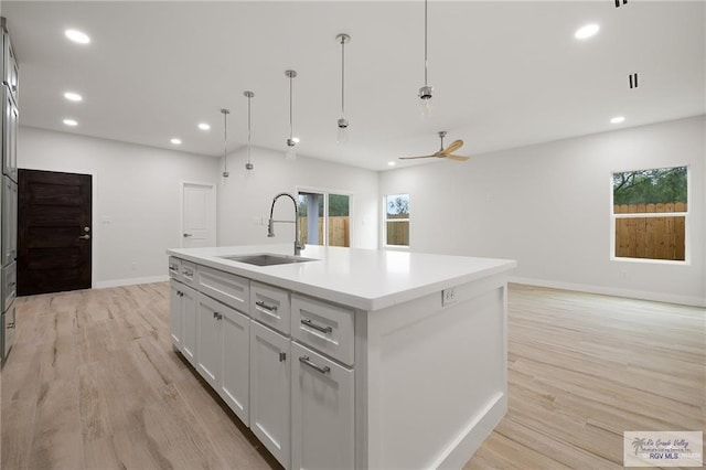 kitchen with white cabinetry, a wealth of natural light, a kitchen island with sink, and sink