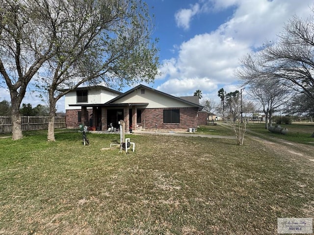 view of front of home with a front yard, brick siding, and fence