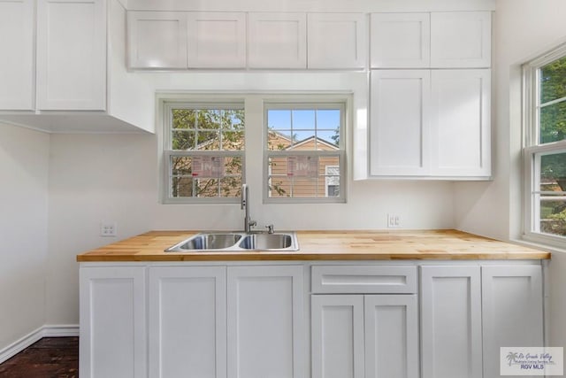 kitchen featuring wood counters, plenty of natural light, white cabinetry, and sink