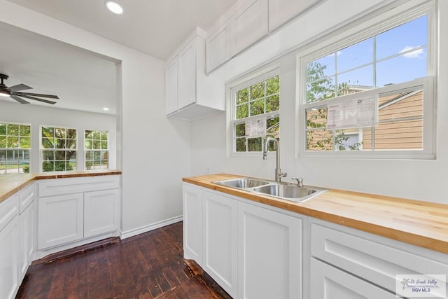 kitchen featuring butcher block countertops, dark hardwood / wood-style floors, white cabinets, and sink