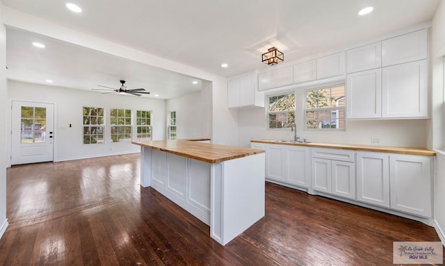 kitchen with white cabinetry, sink, a center island, ceiling fan, and wooden counters