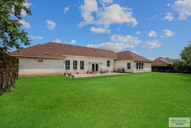 25142 Teal Cir, San Benito, TX 78586 - back of house featuring french doors, a lawn, a fenced backyard, brick siding, and a patio area