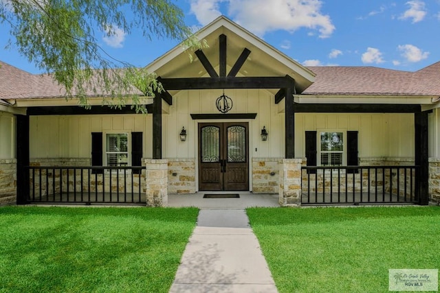 25142 Teal Cir, San Benito, TX 78586 - entrance to property with a yard, stone siding, french doors, and roof with shingles