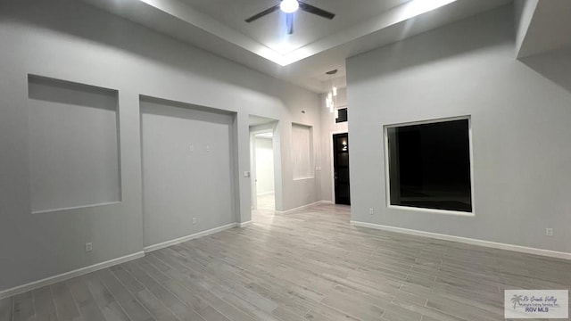 spare room with a high ceiling, light wood-type flooring, and ceiling fan