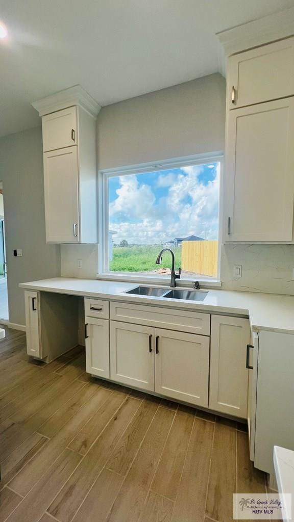 kitchen featuring decorative backsplash, white cabinetry, sink, and light hardwood / wood-style floors