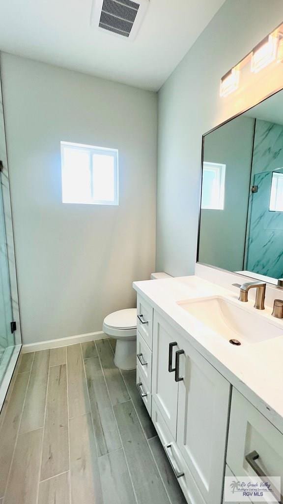 bathroom with a shower, vanity, hardwood / wood-style flooring, and toilet