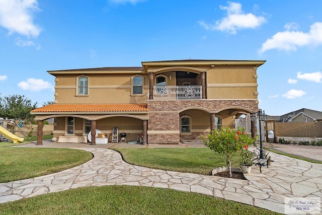 rear view of house featuring a balcony, a yard, and a patio area