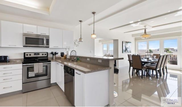 kitchen featuring kitchen peninsula, white cabinetry, pendant lighting, and appliances with stainless steel finishes