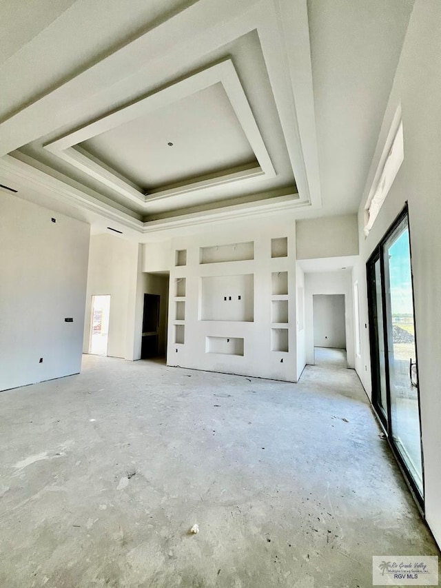 unfurnished living room with built in shelves and a tray ceiling