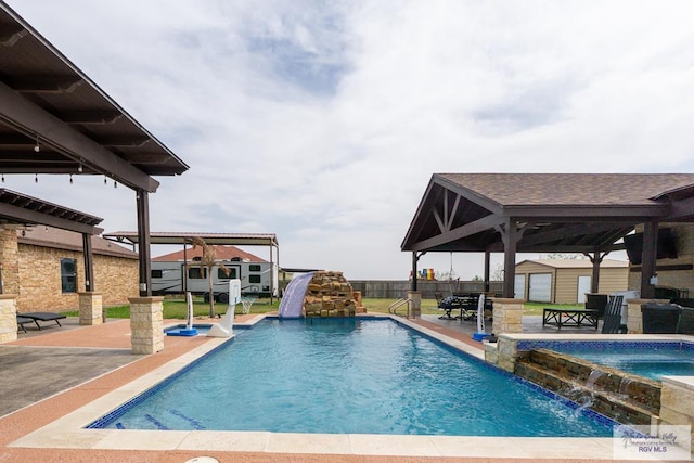 view of swimming pool featuring a patio area, a water slide, an outdoor structure, and fence