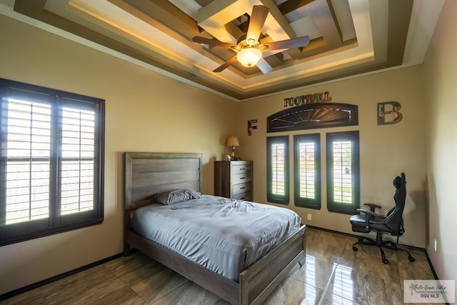 bedroom with a ceiling fan, a tray ceiling, crown molding, and baseboards