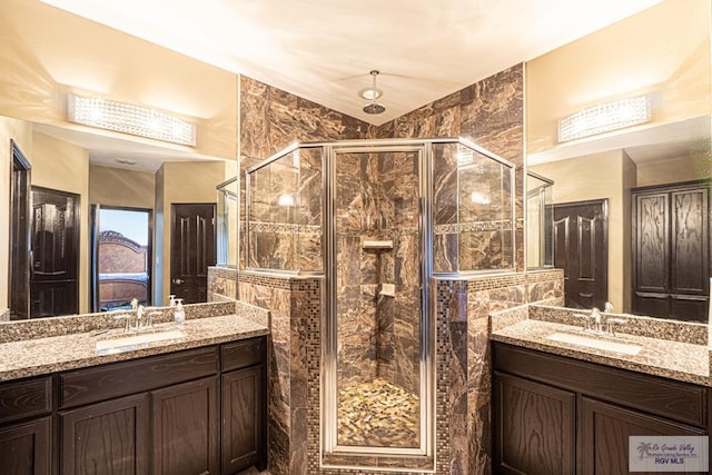 full bath featuring two vanities, a sink, and a shower stall