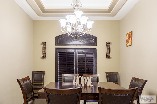 dining space with a chandelier and a raised ceiling