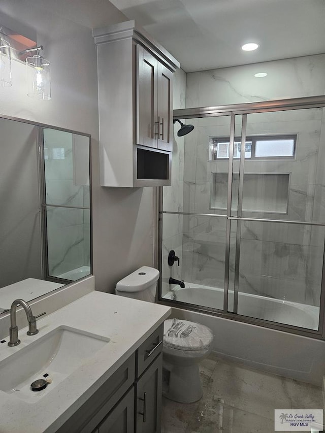 bathroom featuring toilet, vanity, and shower / bath combination with glass door