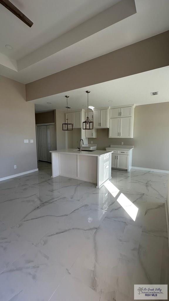 unfurnished living room featuring visible vents, marble finish floor, baseboards, and a sink